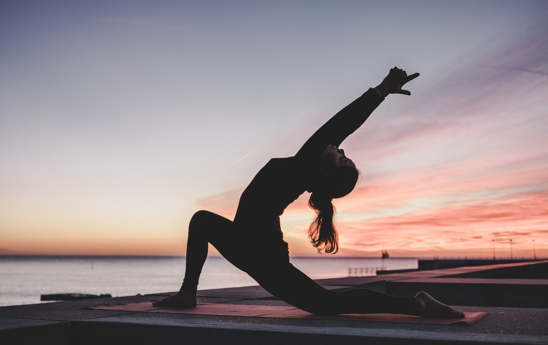 A woman doing yoga at sundown to help manage her stress