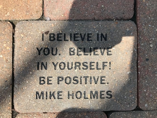 the words 'I believe in you. Believe in yourself! Be positive. Mike Homes' on a brick