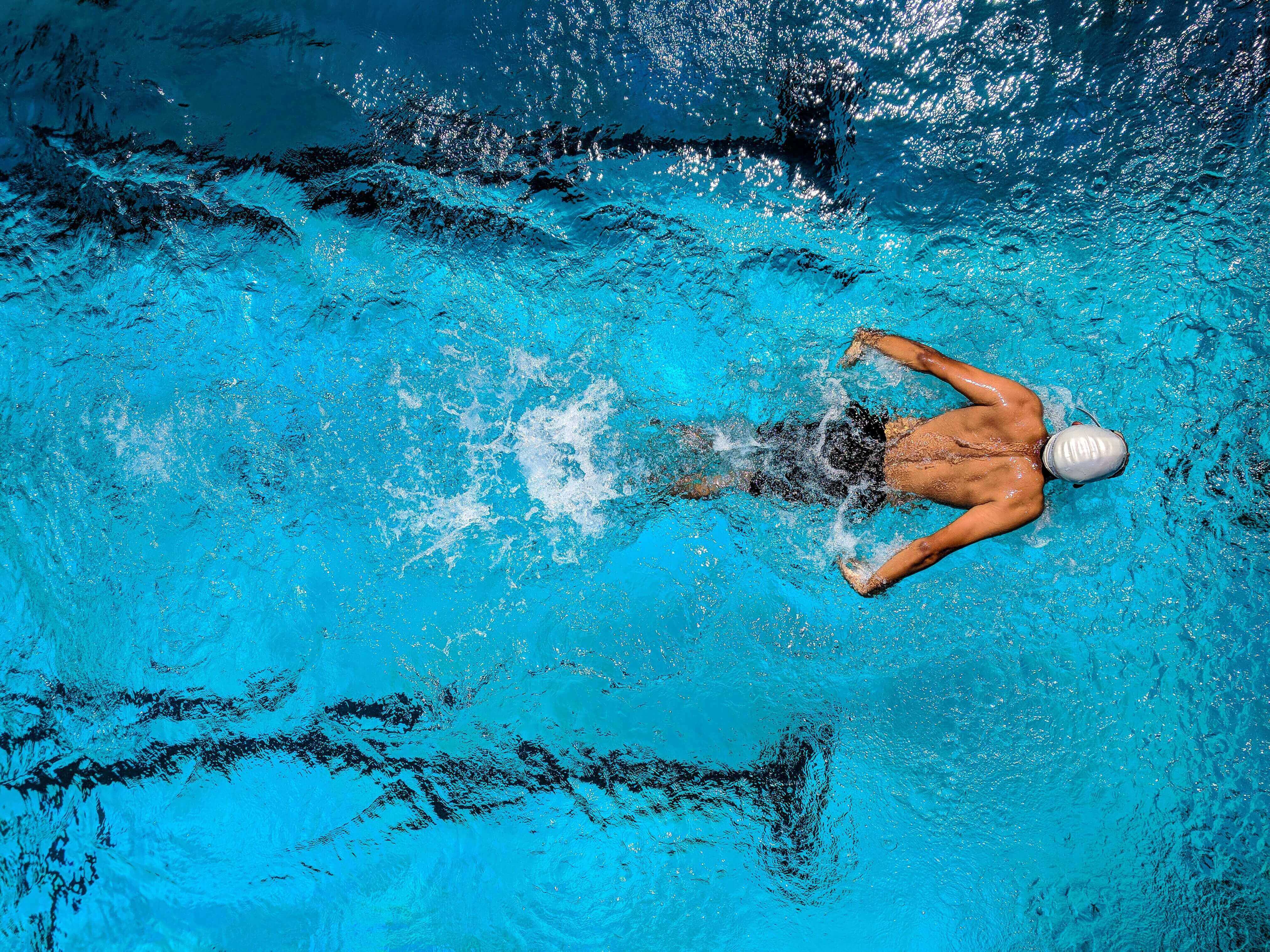 An athlete gliding powerfully through a swimming pool, strong and injury free thanks to Revive compression therapy.
