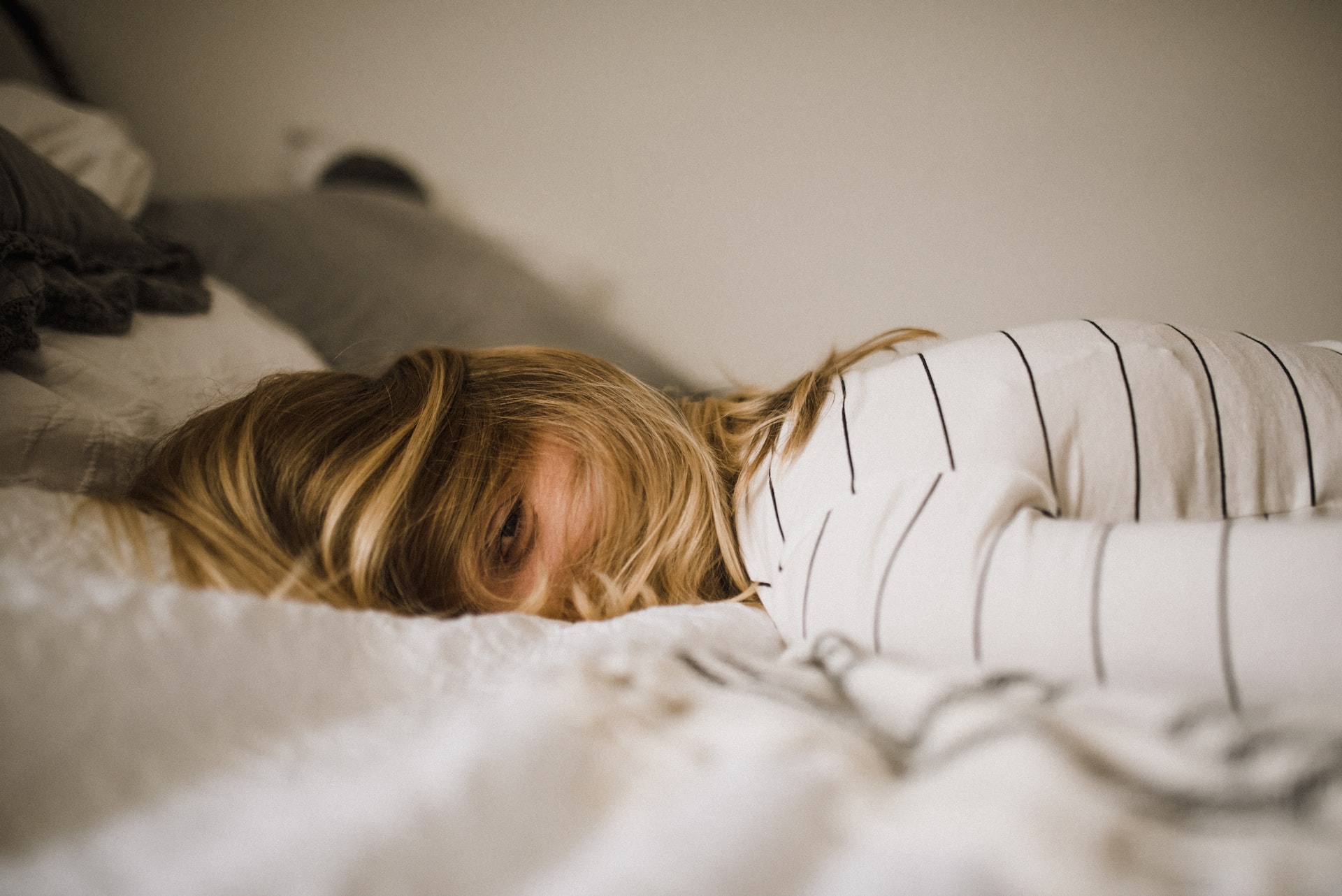 Woman lying in bed with hair in face, exhausted from anxiety