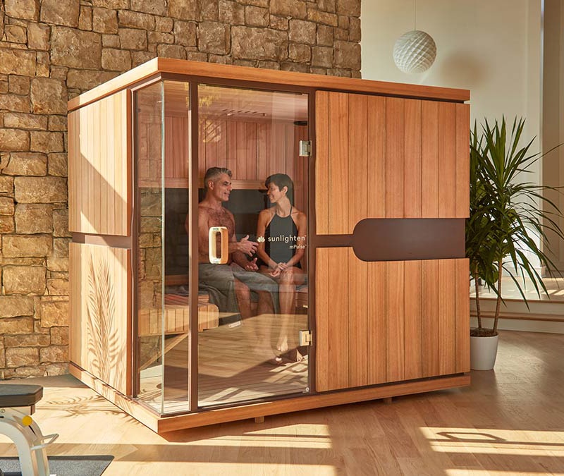 a middle aged man and woman relaxing and chatting inside a infrared sauna showing the five benefits of using one.