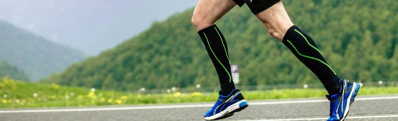 A man running on a running track wearing compression therapy socks