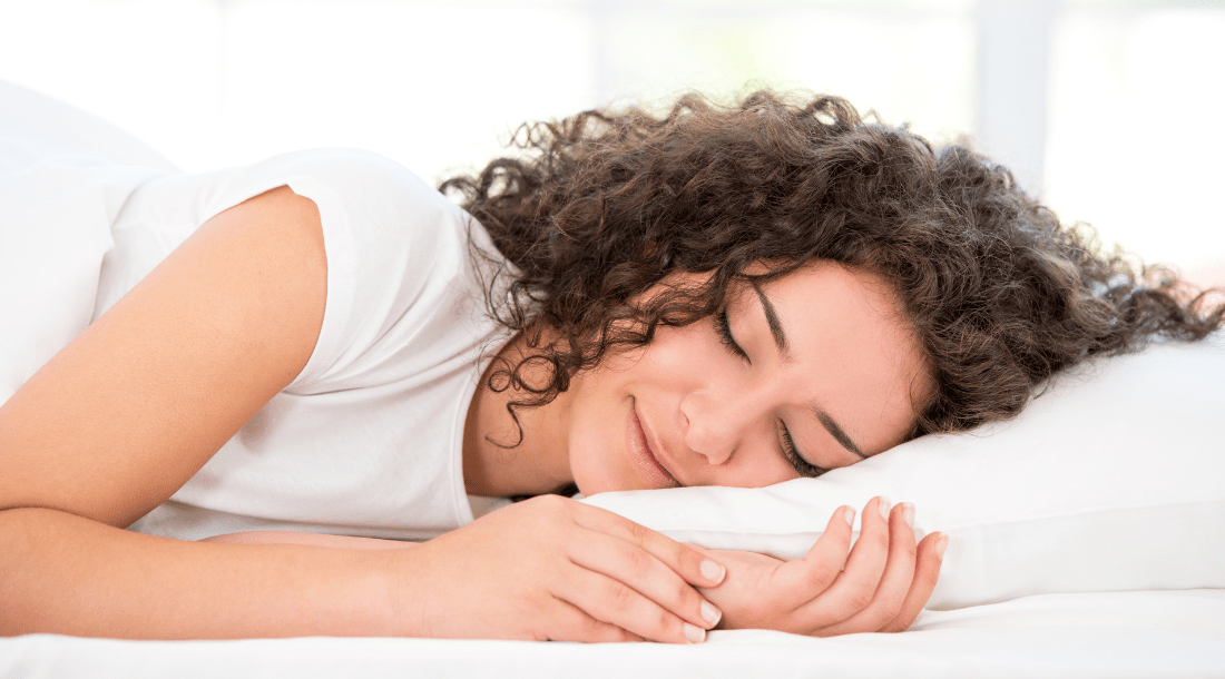 Woman sleeping deeply and peacefully with a smile on her face, exemplifying the benefits of our revolutionary sleep program.